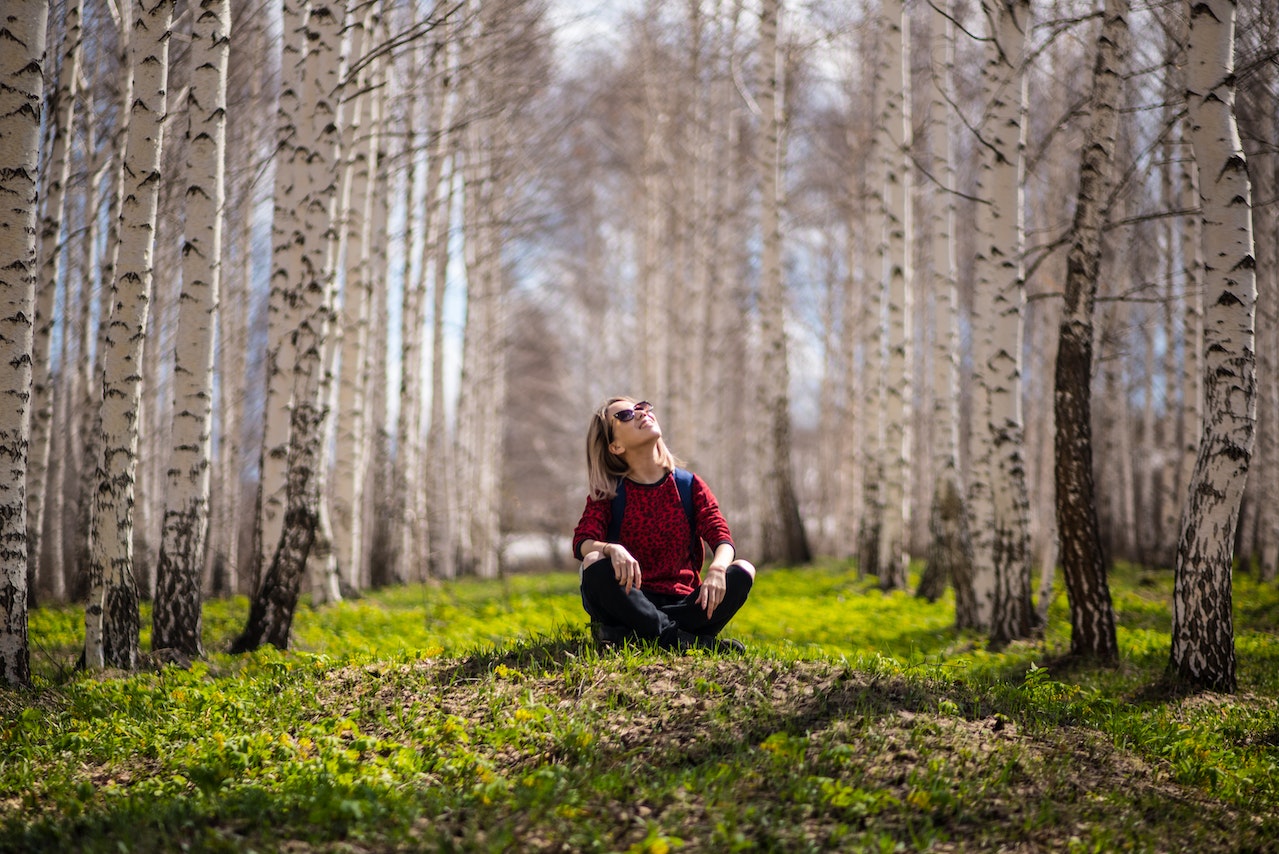 imagem com uma mulher sentada em meio a uma floresta refletindo sobre Responsabilidade ambiental