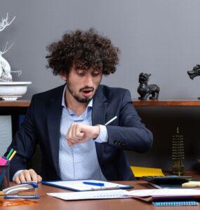 Homem em ambiente corporativo olhando para o relógio.