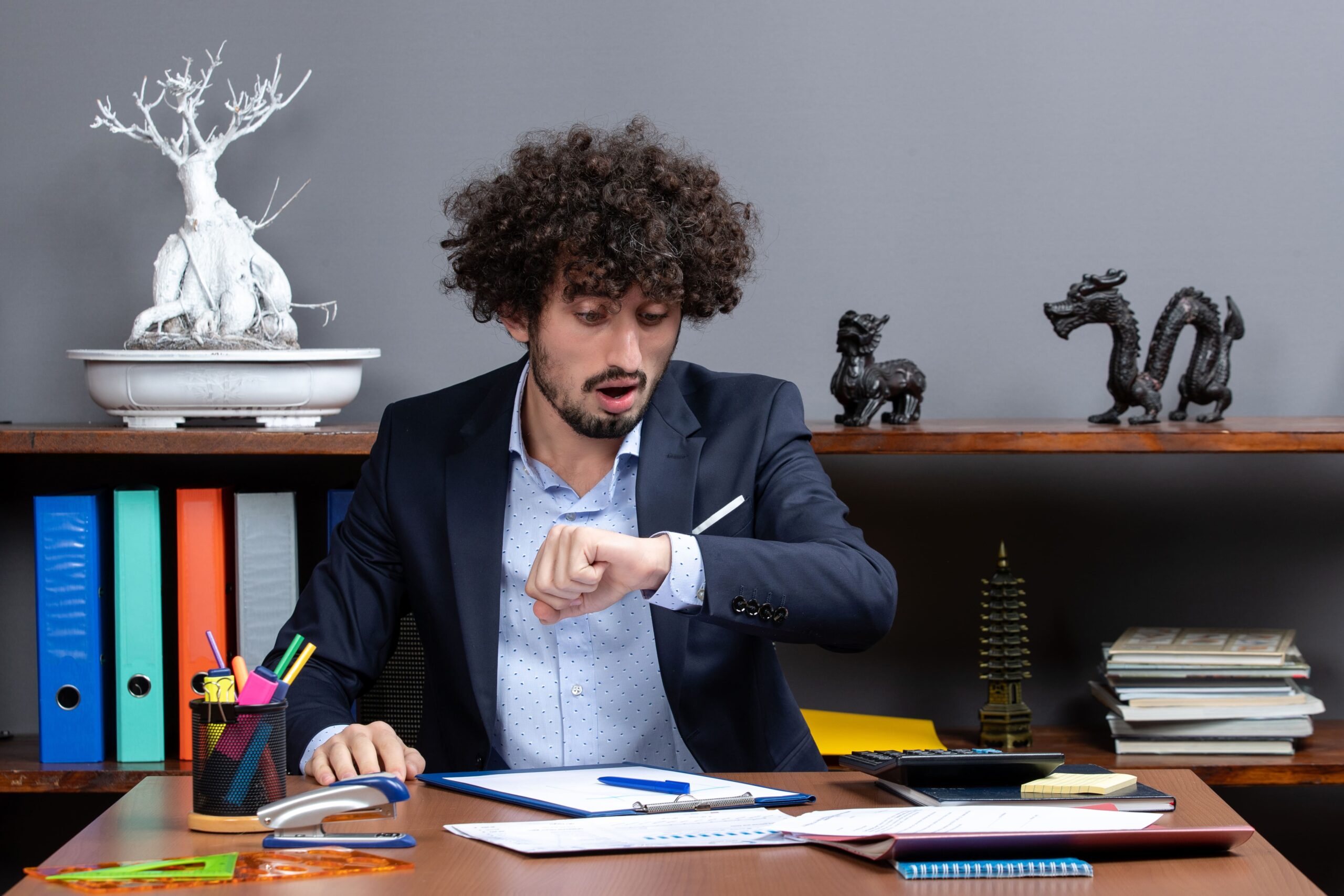 Homem em ambiente corporativo olhando para o relógio.