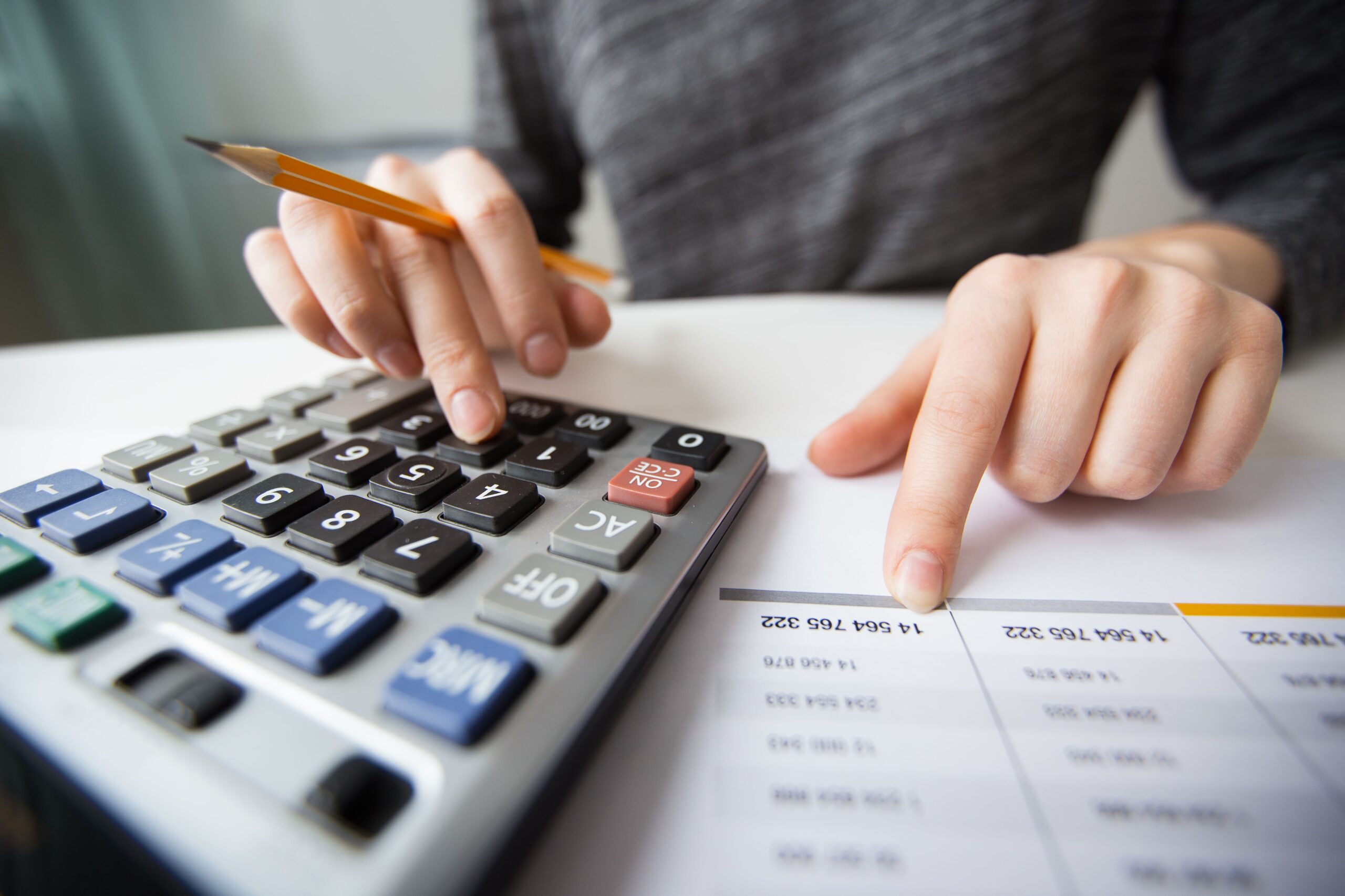 Pessoa em ambiente corporativo fazendo cálculos em uma calculadora, representando o controle de custos no Asana.