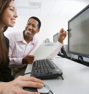 Homem negro mostrando banco de horas para servidor publico em computador para mulher que usa o computador