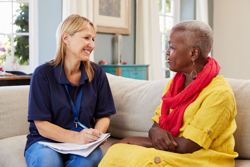 Female support worker visits senior woman at home.