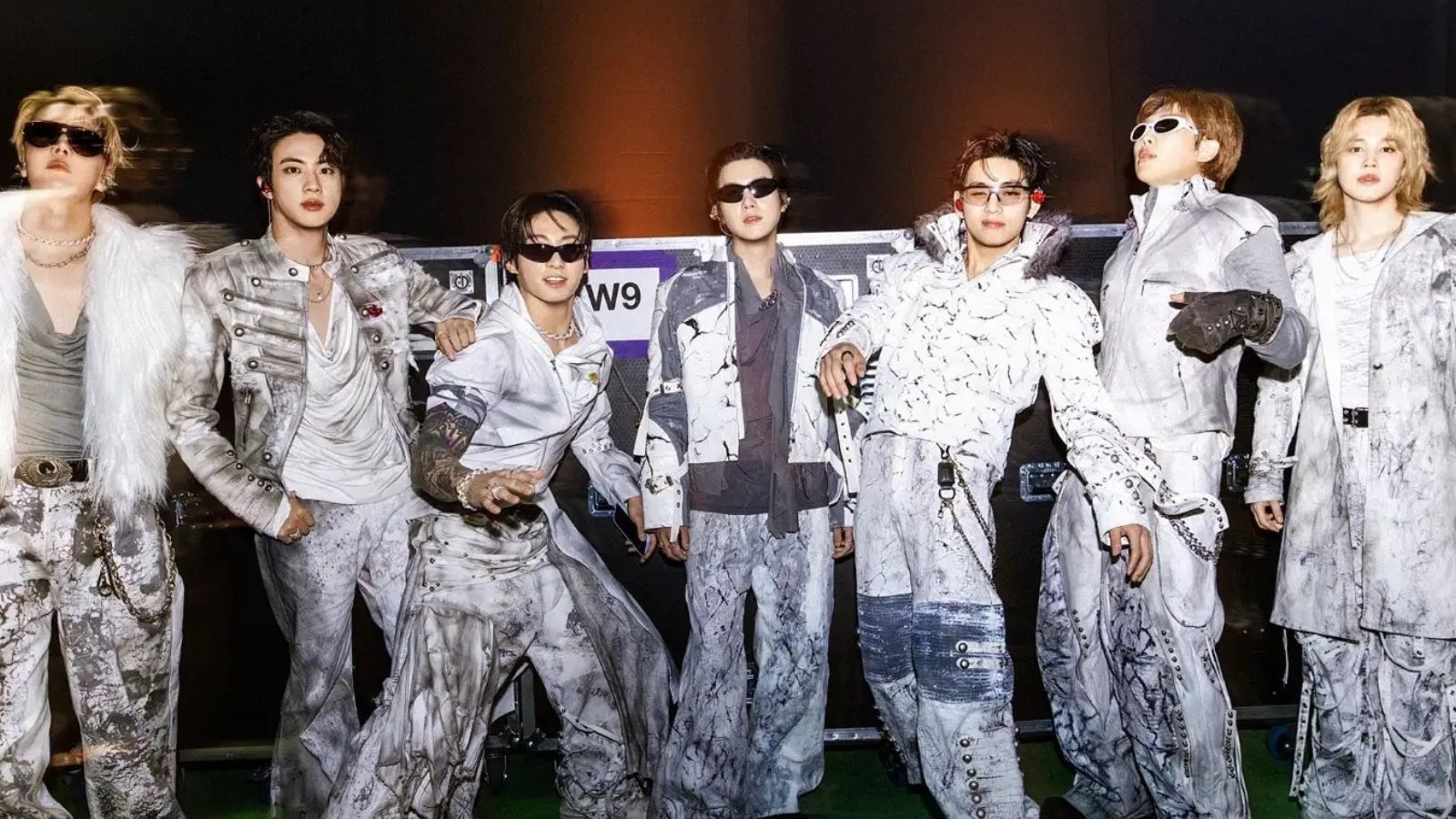 Integrantes do BTS posando juntos com roupas claras e óculos escuros em imagem de divulgação da era ARIRANG