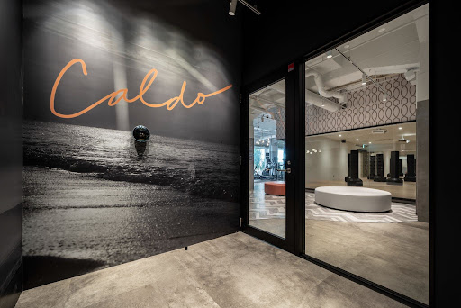 株式会社INSPAが運営するホットヨガスタジオ「CALDO（カルド）」銀座ナイン店の入口。ガラス越しに明るいスタジオ内観が見える様子