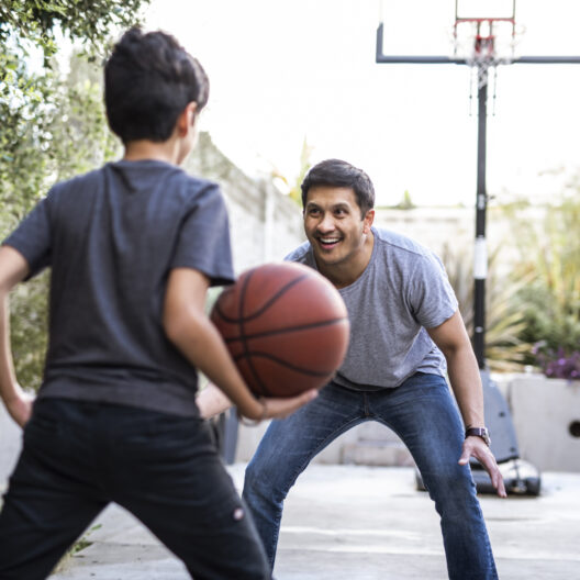 Man plays basketball with young son