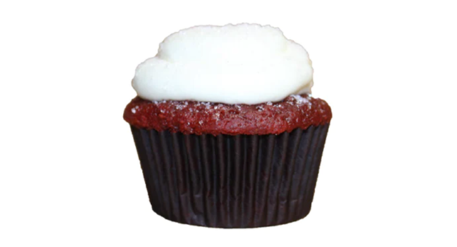 A closeup of a red velvet cupcake topped with cream cheese