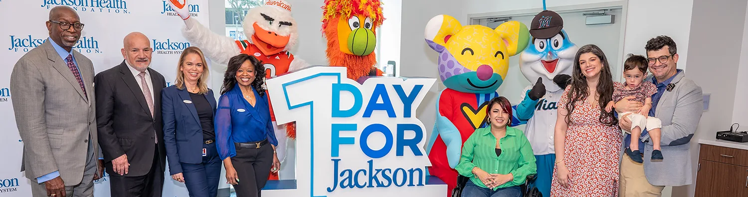 A group of people next to a sign that reads 1 Day for Jackson. One Day of giving. Everyday miracles.