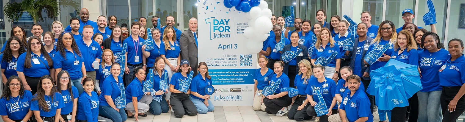 Large group of people posing and smiling at the camera while wearing blue Jackson Health System t-shirts