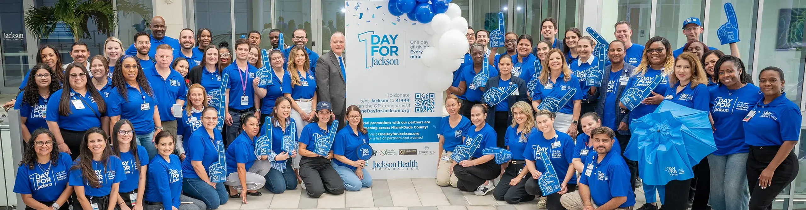 Large group of people posing and smiling at the camera while wearing blue Jackson Health System t-shirts