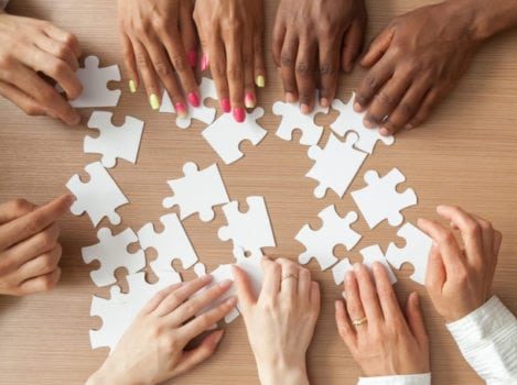 Multiple hands building a jigsaw