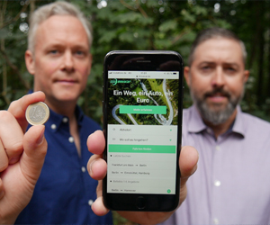 Movacar Webseite Eustach von Wulffen und Karl Markiewicz halten eine Euromünze und ein Handy mit der Movacar-Seite darauf