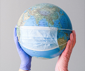 eine Person, die einen Globus mit Handschuhen hält und der Globus hat eine Maske