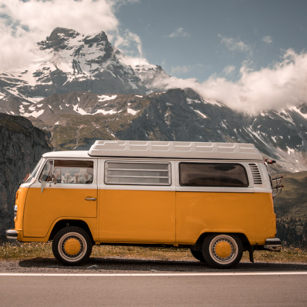 Camperbus in organge und weiß vor einem Bergpanorama