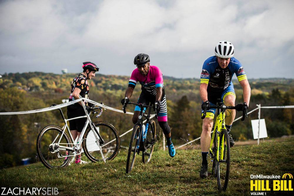 Two cyclocross racers remount their bikes after a steep run-up overlooking the Root River Valley.