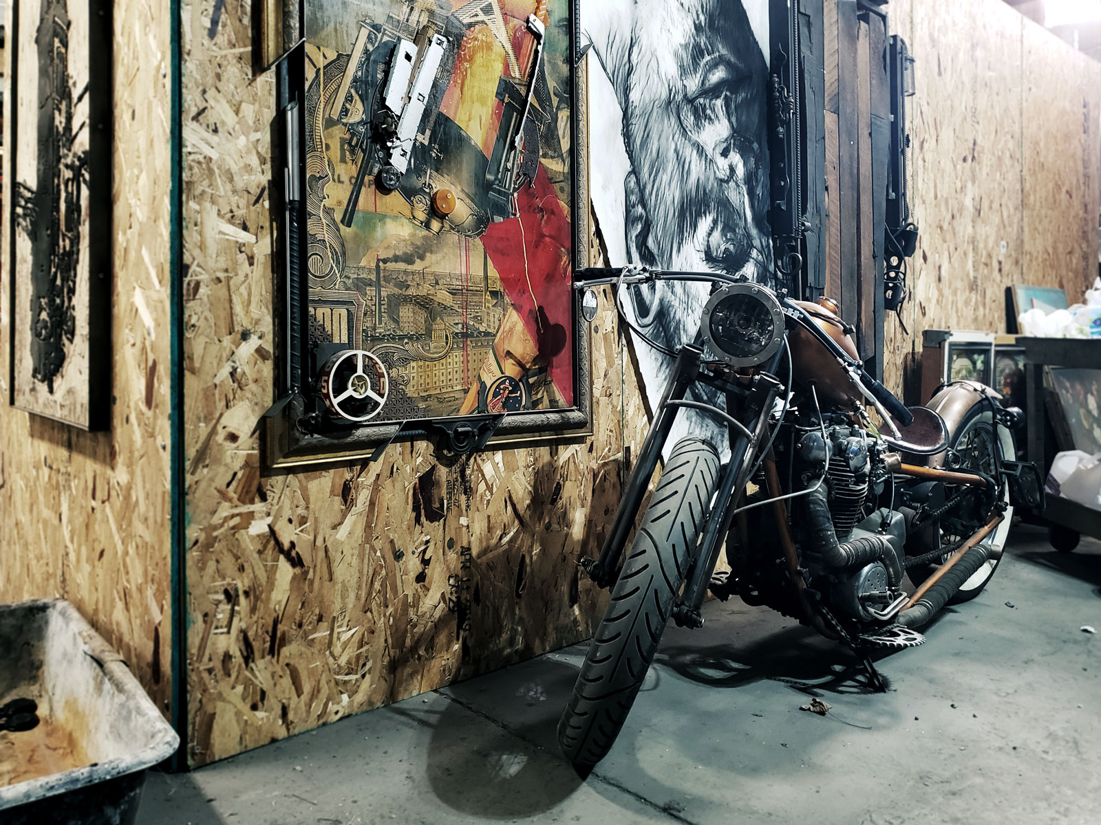 A motorcycle parked next to the industrial prints of Brandon Minga.