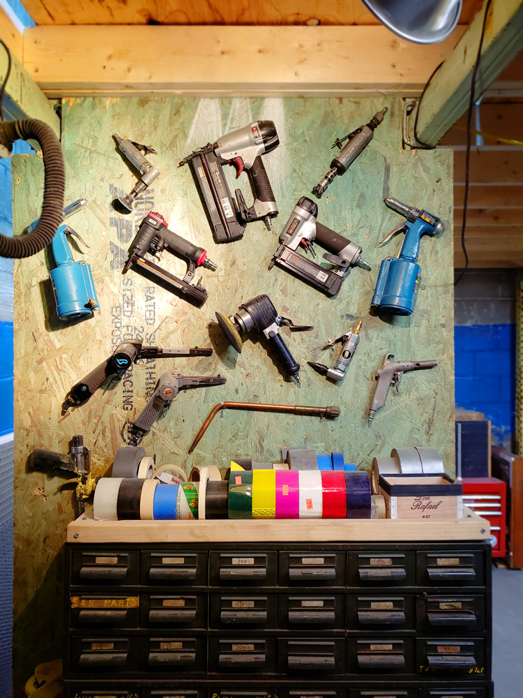 Power tools arranged artfully on a peg board sit above organizational drawers.