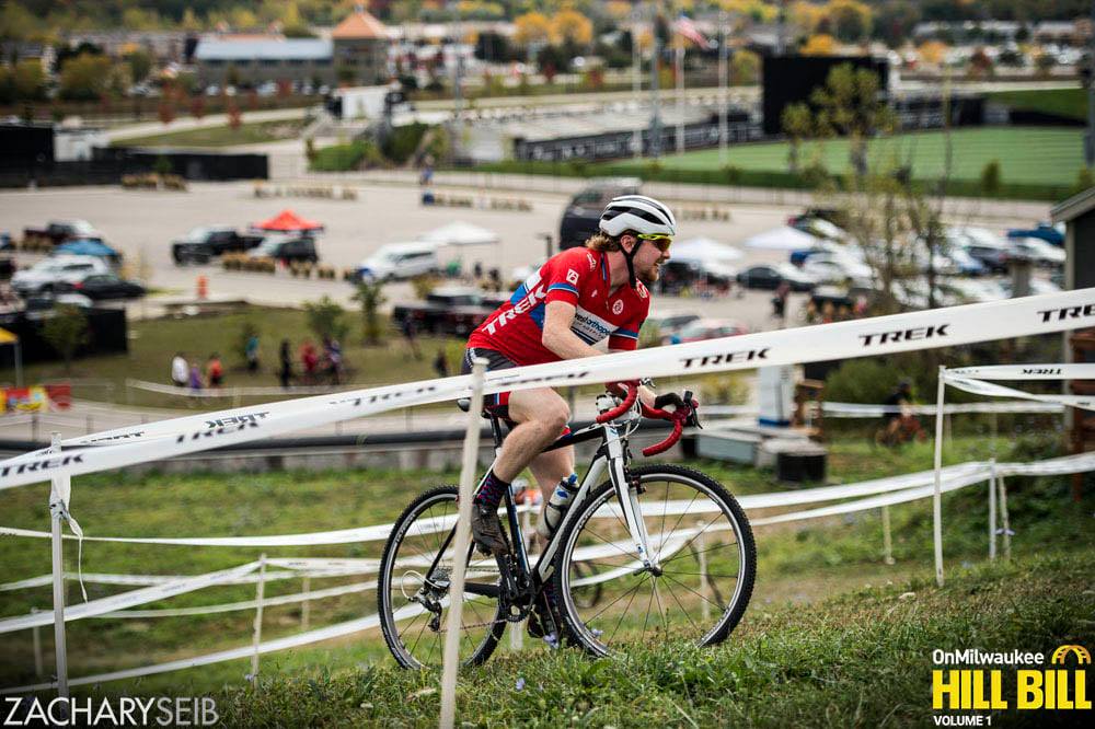 A cyclocross racer ascends a hill overlooking the main staging area.