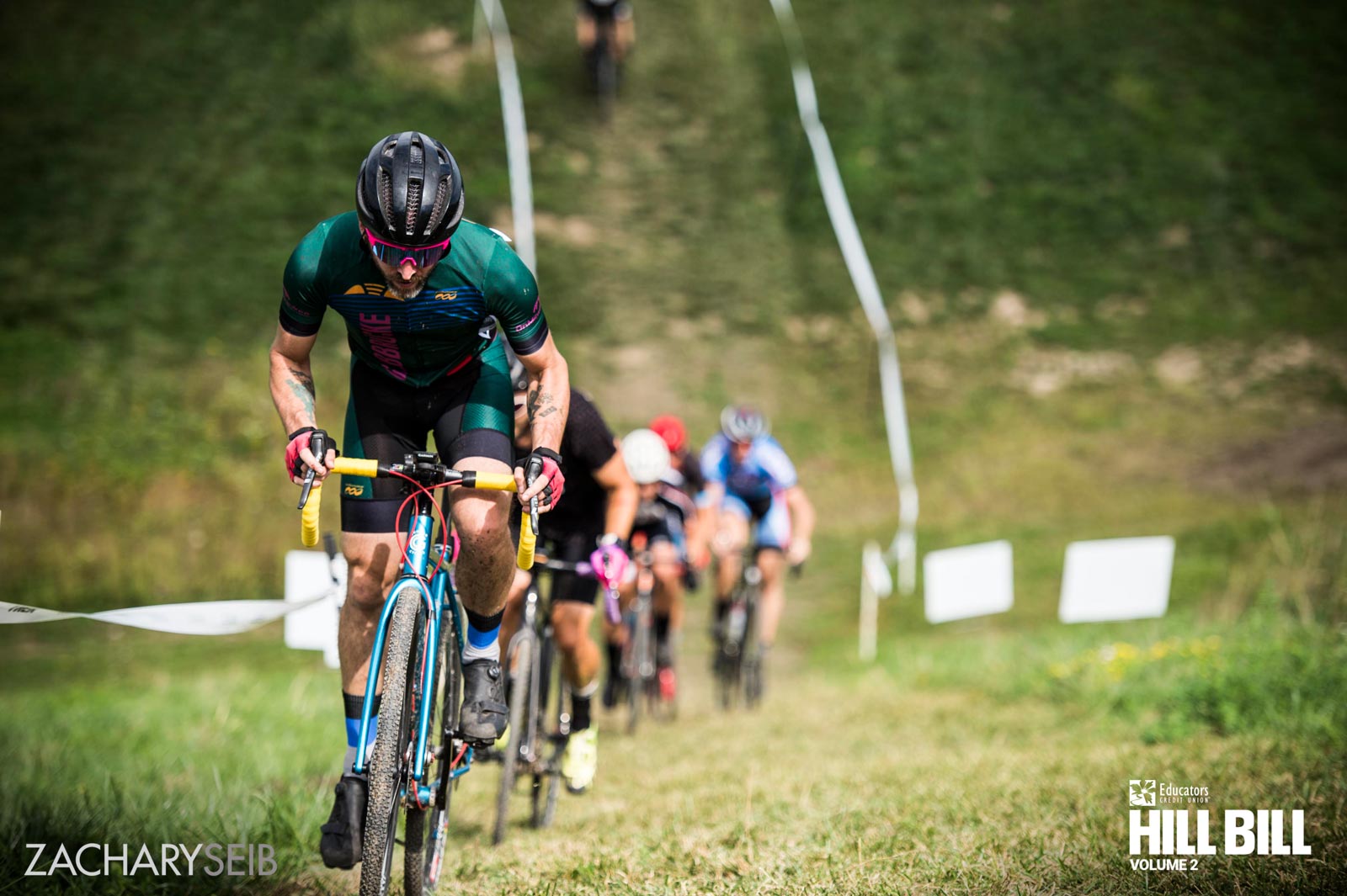 A line of cyclocross racers riding up a steep hill.