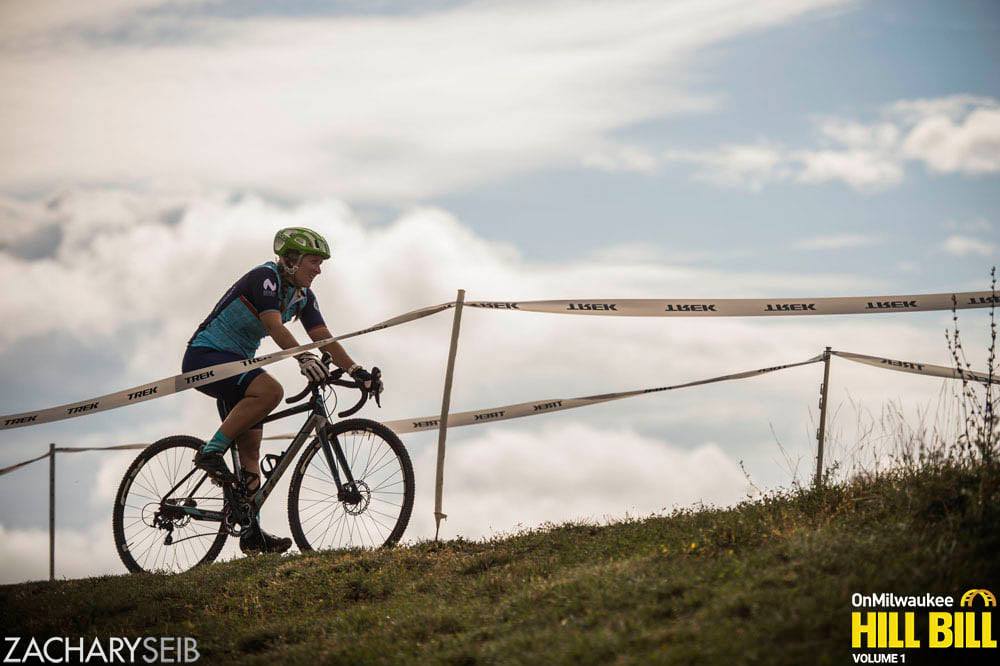 A cyclocross racer, back lit by beautiful clouds.