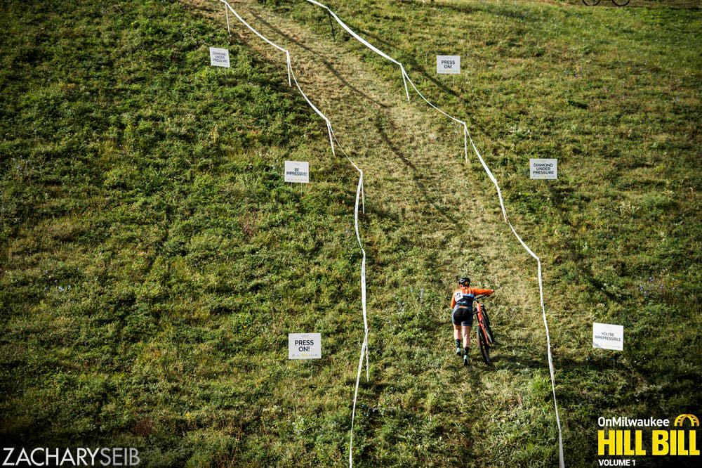 A cyclocross racer pushes her bike up a very steep, wall-like the run-up.