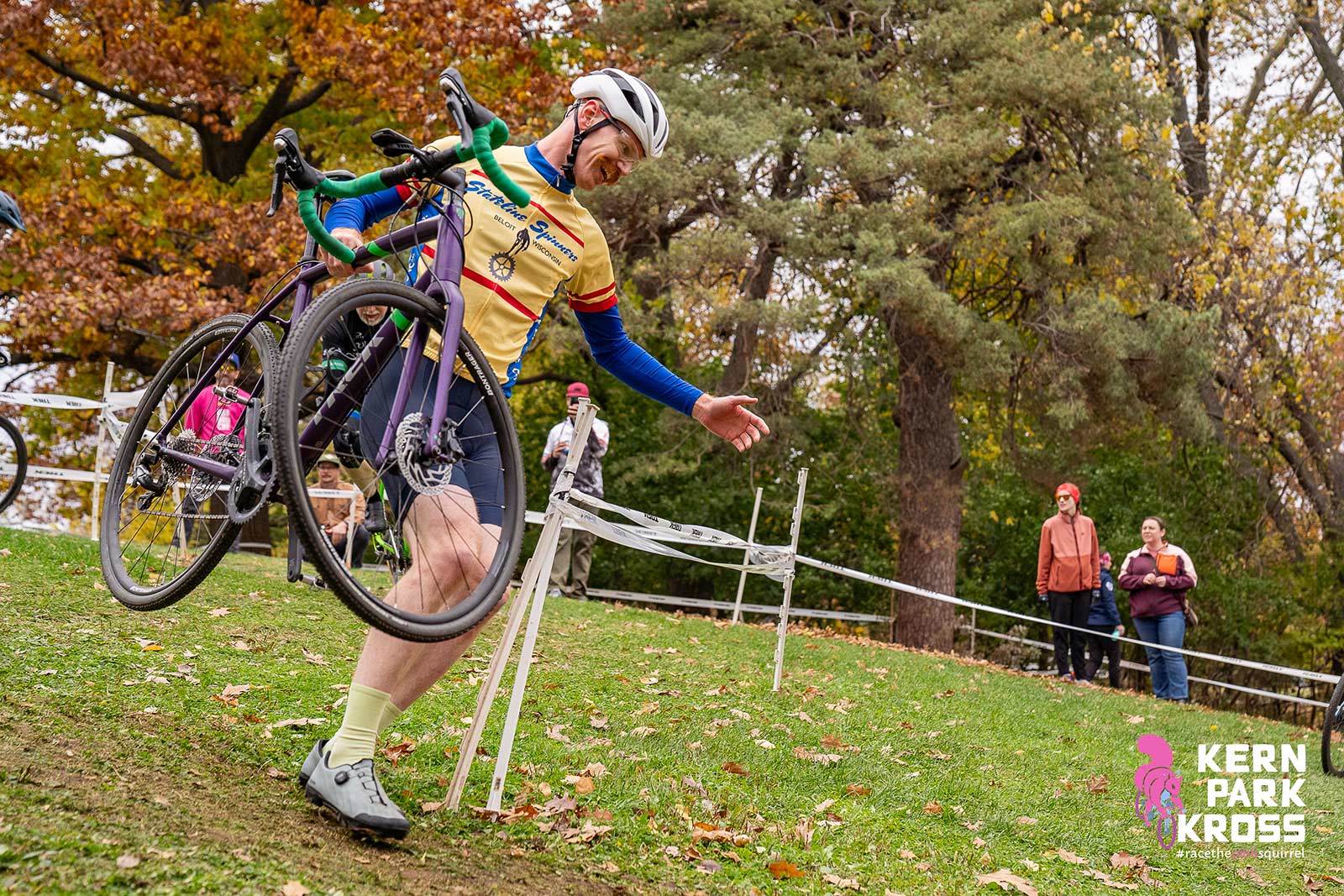 A man with a mustache runs with his bike around an off-camber turn.