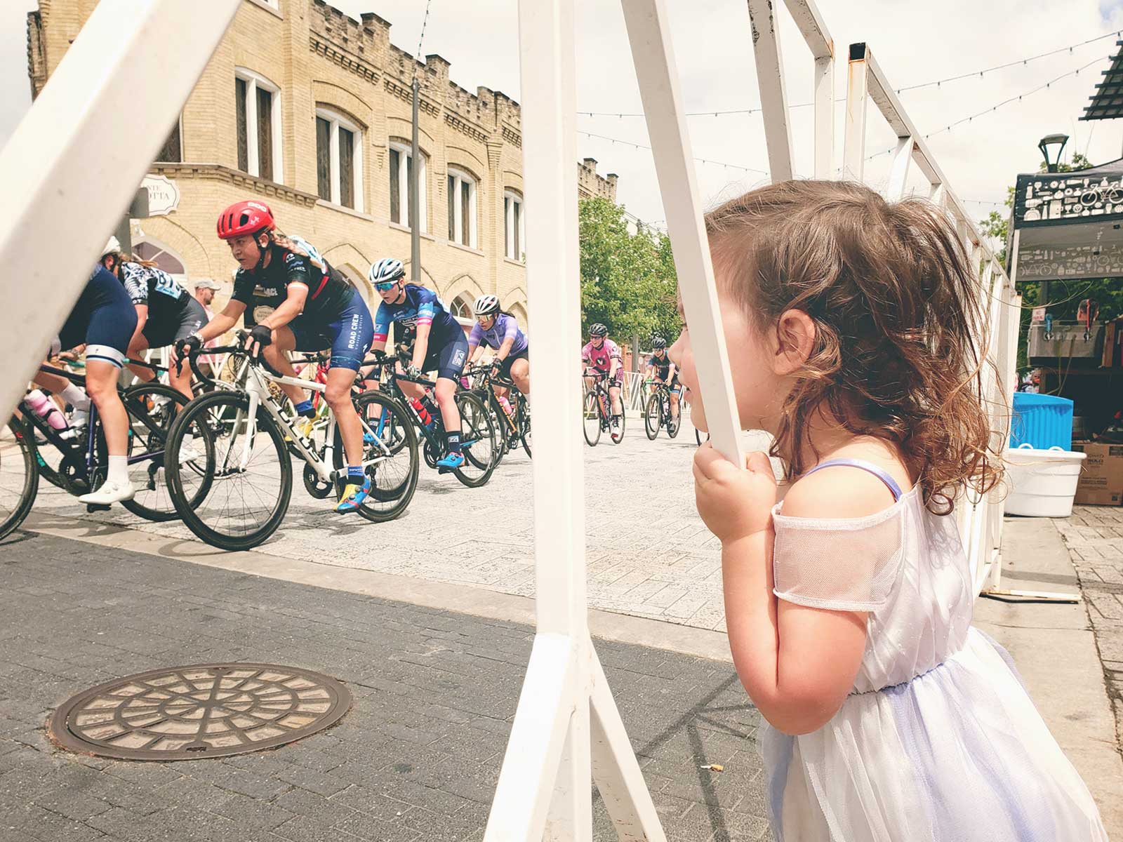 A little girl watches a bike race through the barriers. Photo by Jason McDowell.