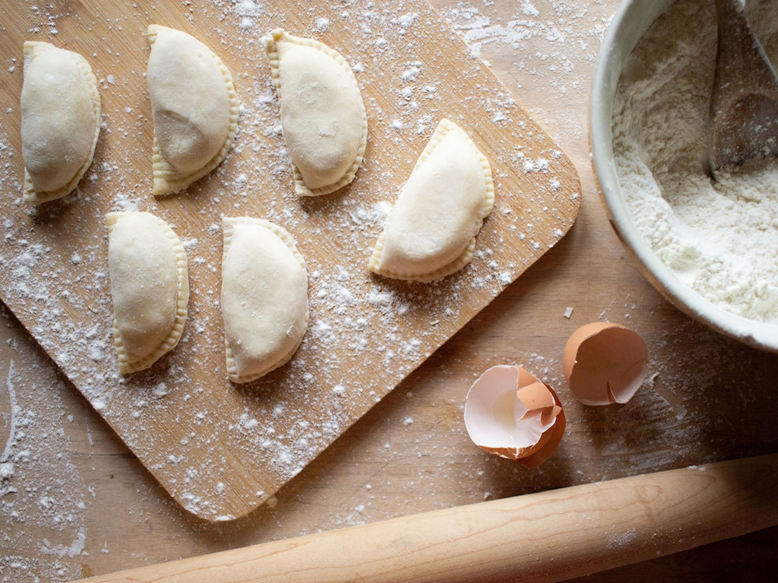 Pierogi on board with broken egg and rolling pin