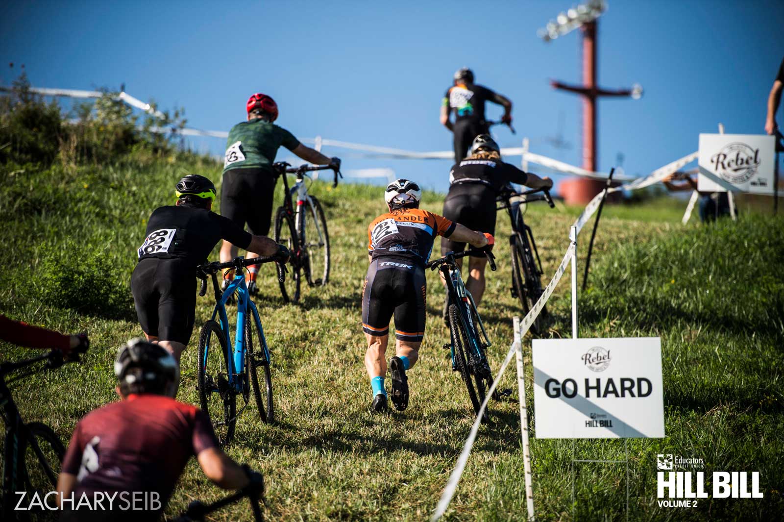 Cyclocross racers pushing bikes up a hill.