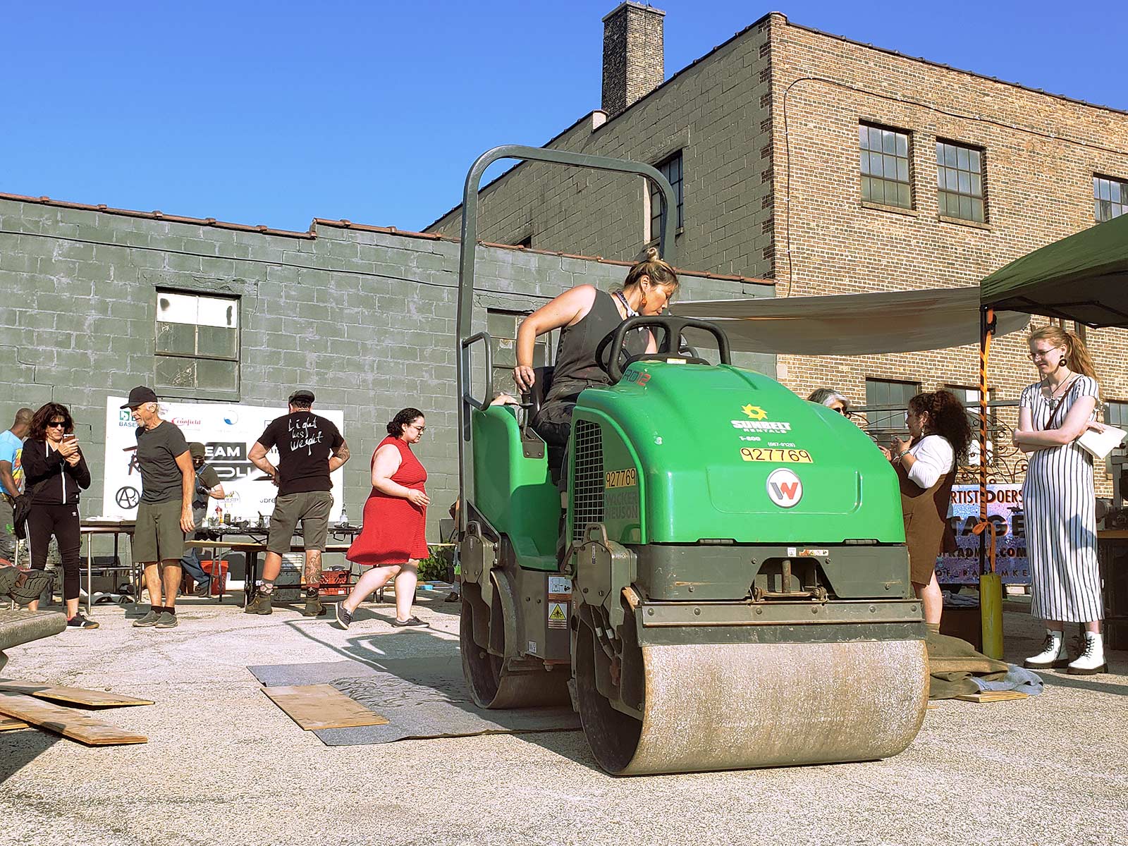 An artist pilots a small steam roller over their woodcut print.