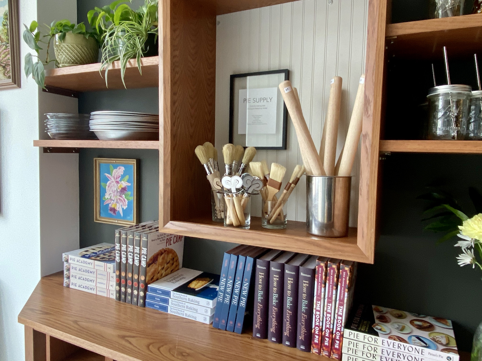 Pie supplies, cookbooks, plants on shelves