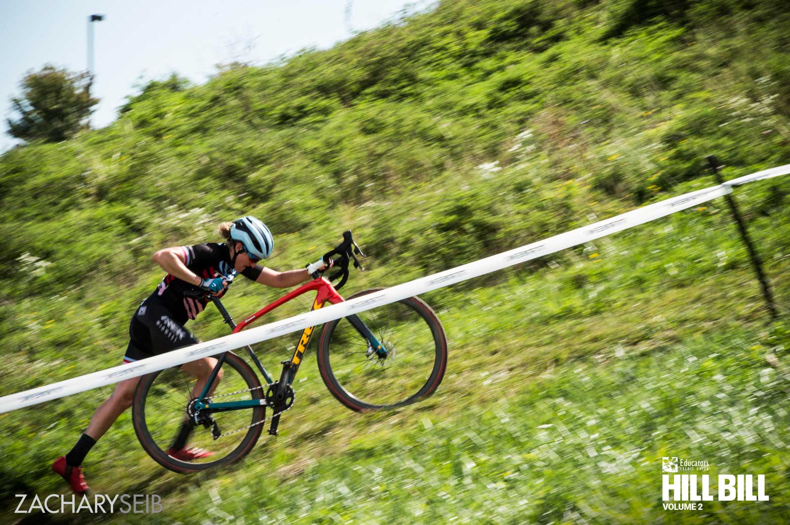 A cyclocross racer pushing a bike up a steep hill.