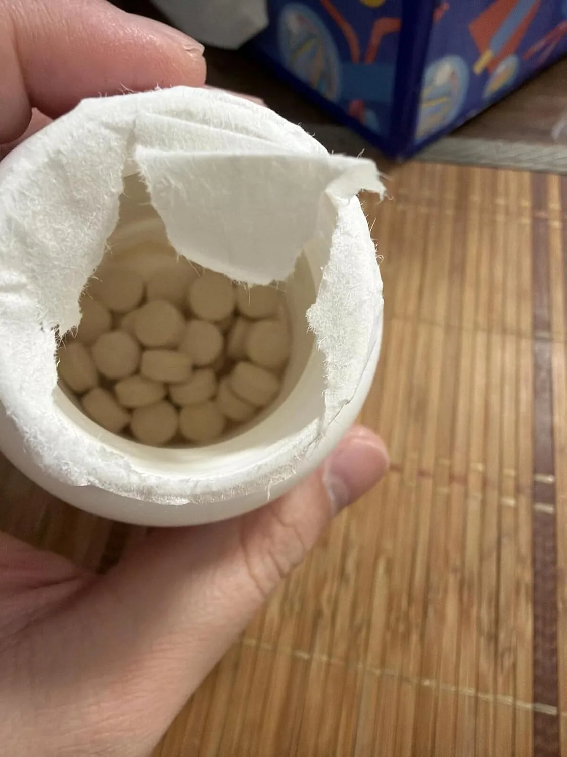 Looking into an opened Synadentix bottle with the cotton safety wadding torn back, revealing tan tablets packed inside