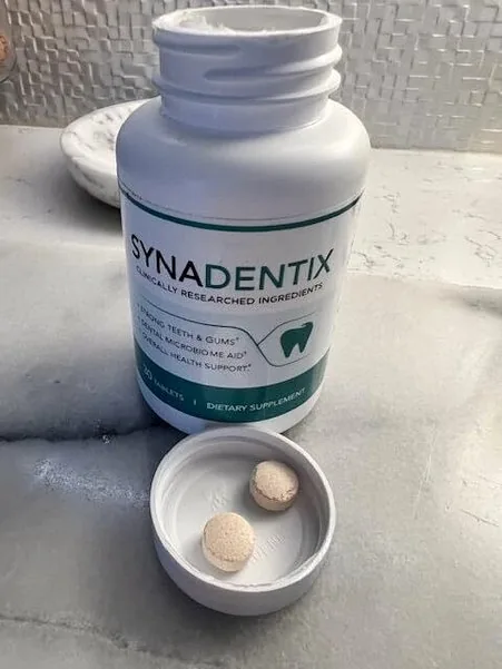 Synadentix bottle on a marble surface with the white cap in front holding two tan tablets