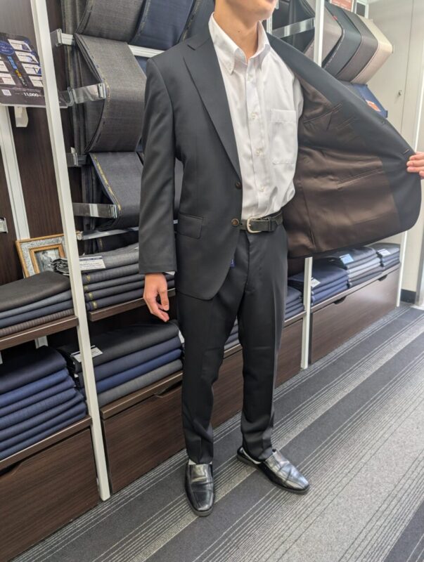 定番の黒無地のスーツで洒落て茶色の装飾を。のアイキャッチ画像