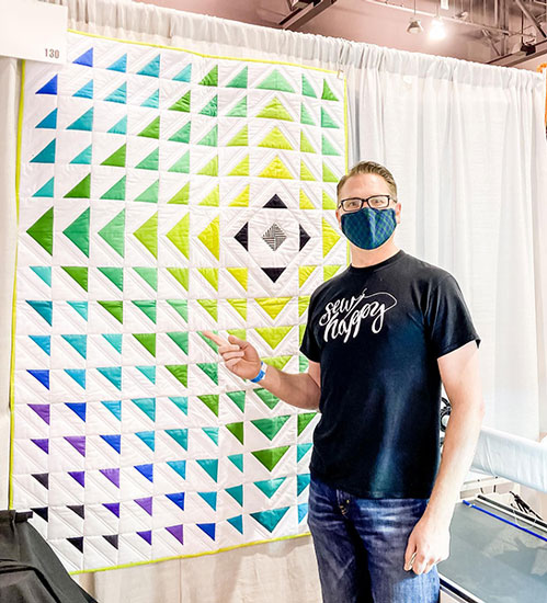 Man standing in front of a quilt
