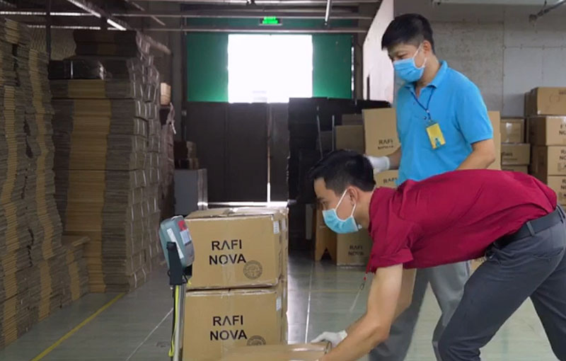 Workers in the Rafi Nova warehouse weighing a box