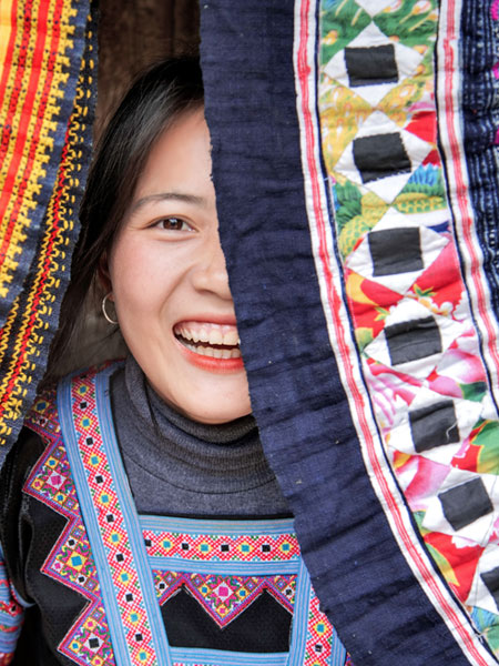 A female smiling in between some Rafi Nova fabrics. 