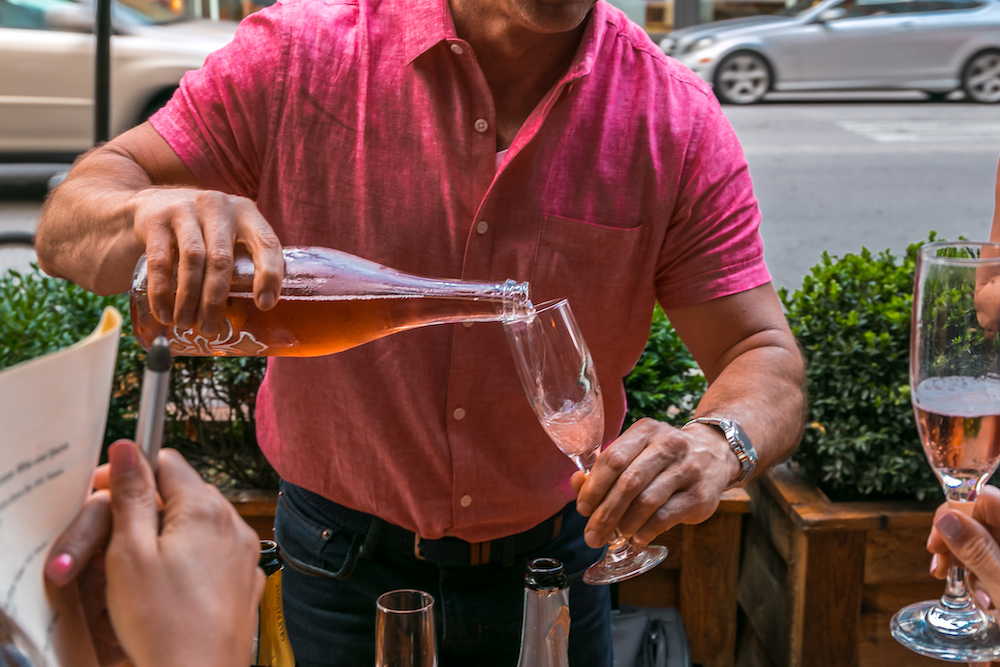 A man pours a sparking Rosé at wine tasting at Osteria Via Stato. Prosecco on the Patio