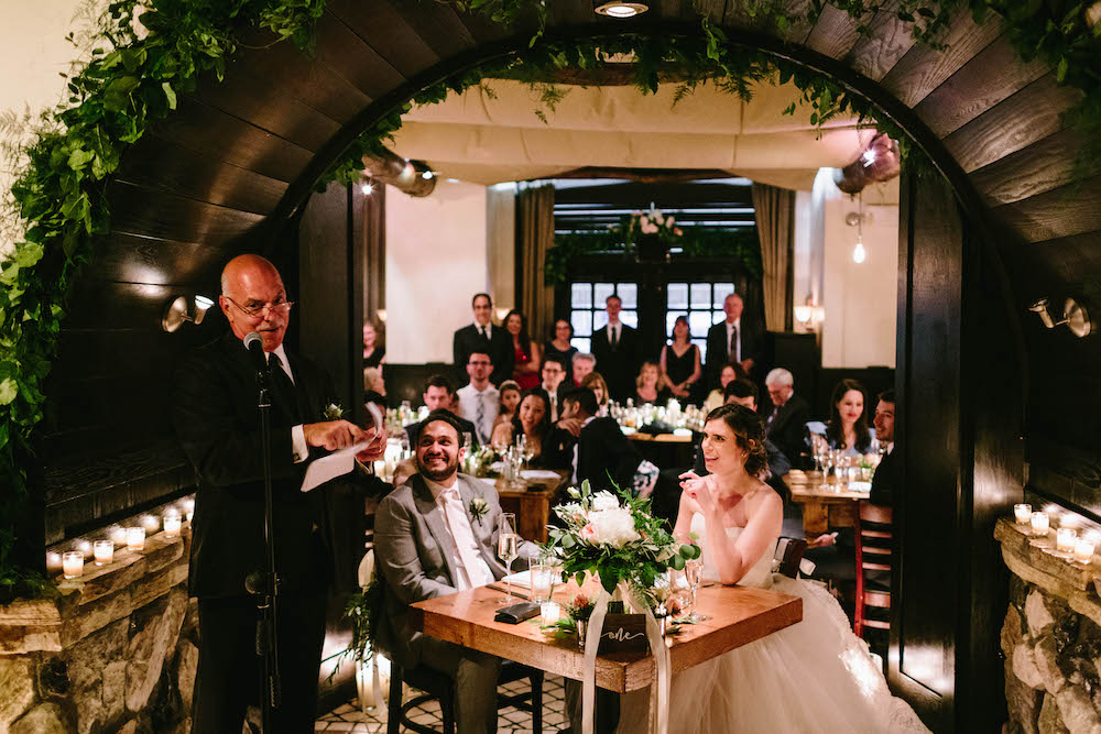 A just married couple listen to guest speeches during wedding reception at Osteria Via Stato.