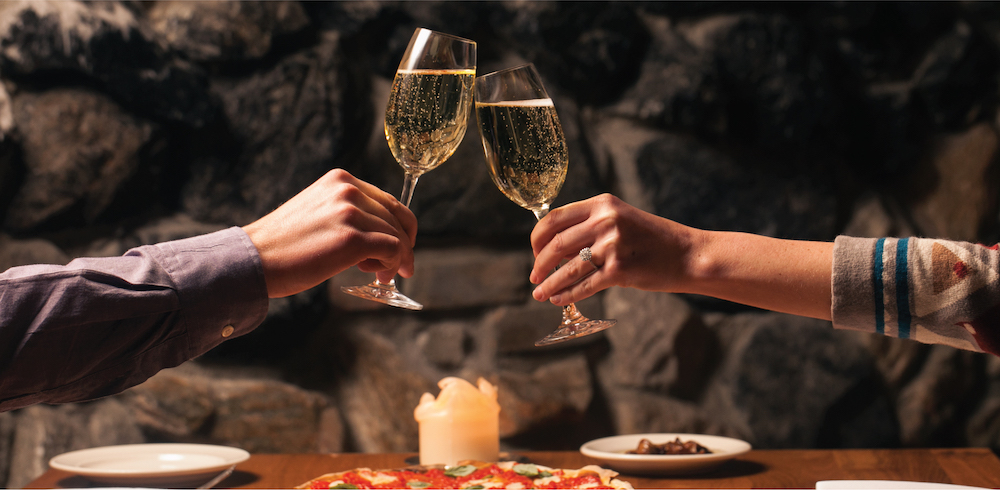 A cheers of Prosecco shared at a table over a meal for two at Osteria Via Stato.