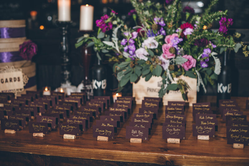 Place cards in wine corks for wedding seating with large floral arrangement