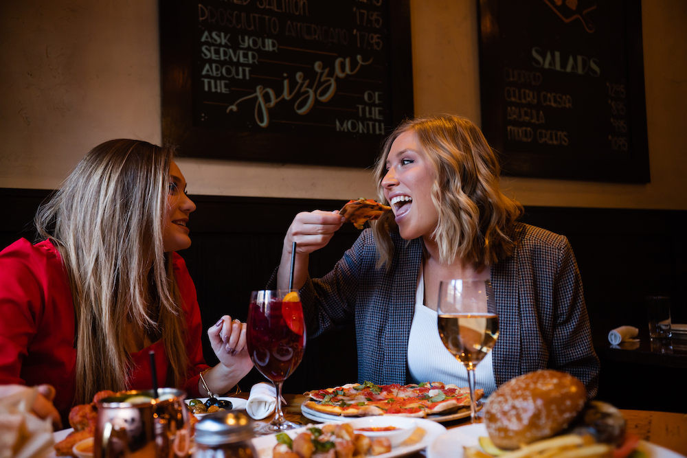 A couple shares a lunch meal with pizza and wine at Osteria Via Stato.