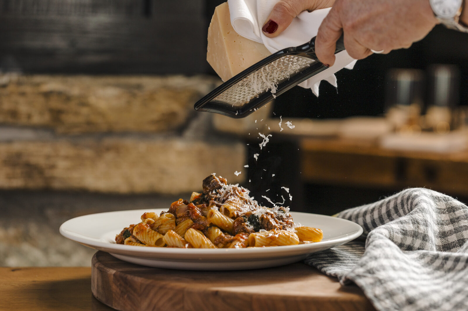 Cheese being shredded over a plate of the Short Rib Rigatoni at Osteria Via Stato.