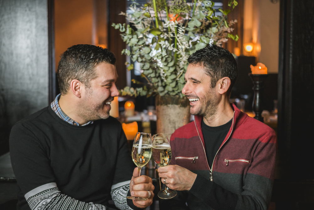 A married couple cheers with two glasses of Prosecco at Osteria via Stato.