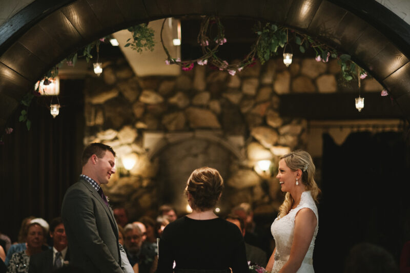 Couple smiling and laughing while getting married; stone wall in back