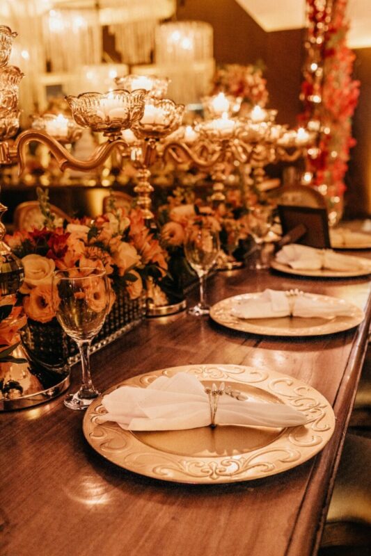 A table set for a wedding with floral, candles, chargers, and place settings.