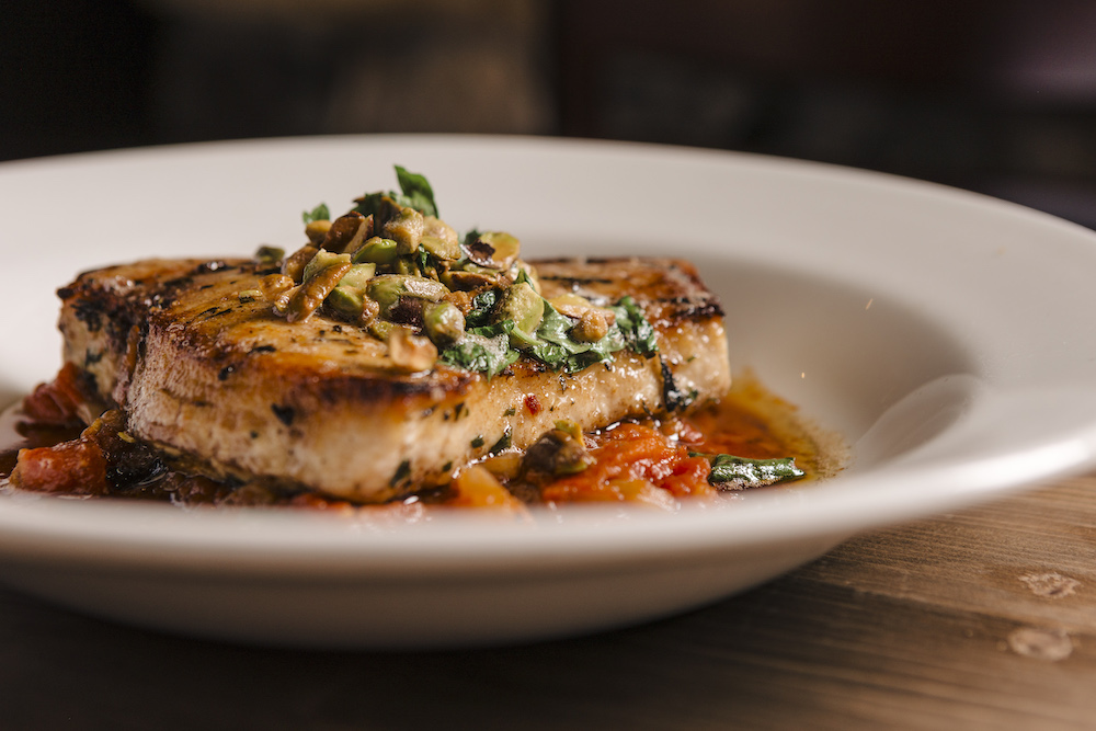 Pan Roasted Swordfish dish plated with pepperonata, crusted pistachios, and herbs at Osteria Via Stato.