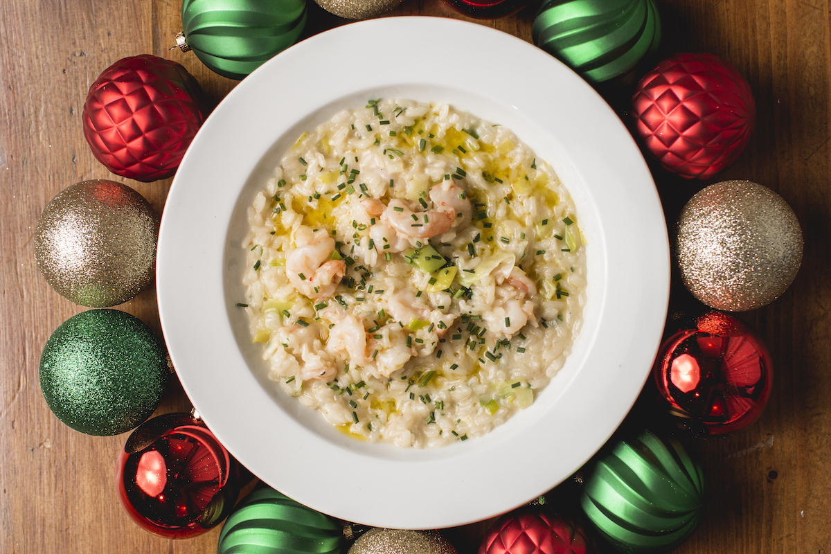 Overhead view of shrimp risotto with Christmas ornaments surrounding bowl.