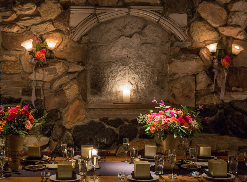 Tables against stone wall with spring color floral in dining room at Osteria Via Stato.