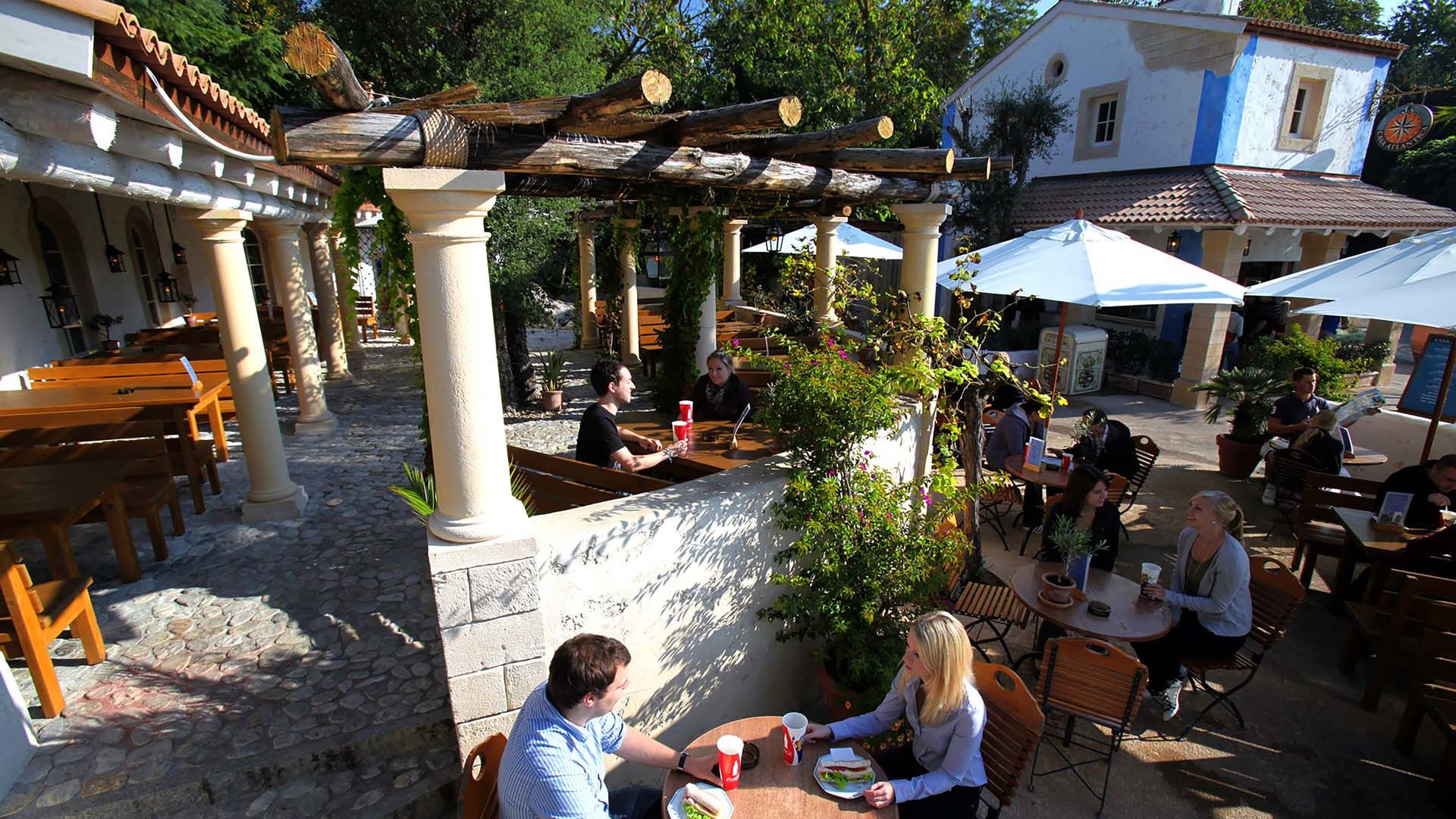 Das Bild zeigt einen, von Säulen umsäumten Outdoor Sitzbereich der eine tolle Aussicht auf den Portugiesischen Themenbereich ermöglicht.